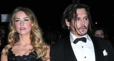 A man and a woman in formal attire at an event, with the woman in a black dress and the man in a tuxedo.