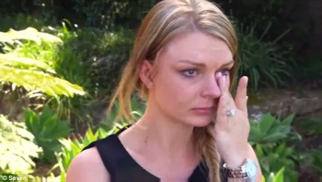 A woman with blonde hair wipes her tears in a garden setting, looking emotional.