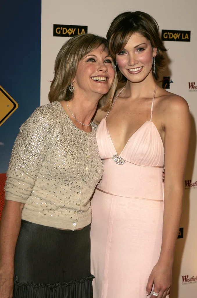 Two women smiling at an event, posing for a photo, elegantly dressed.