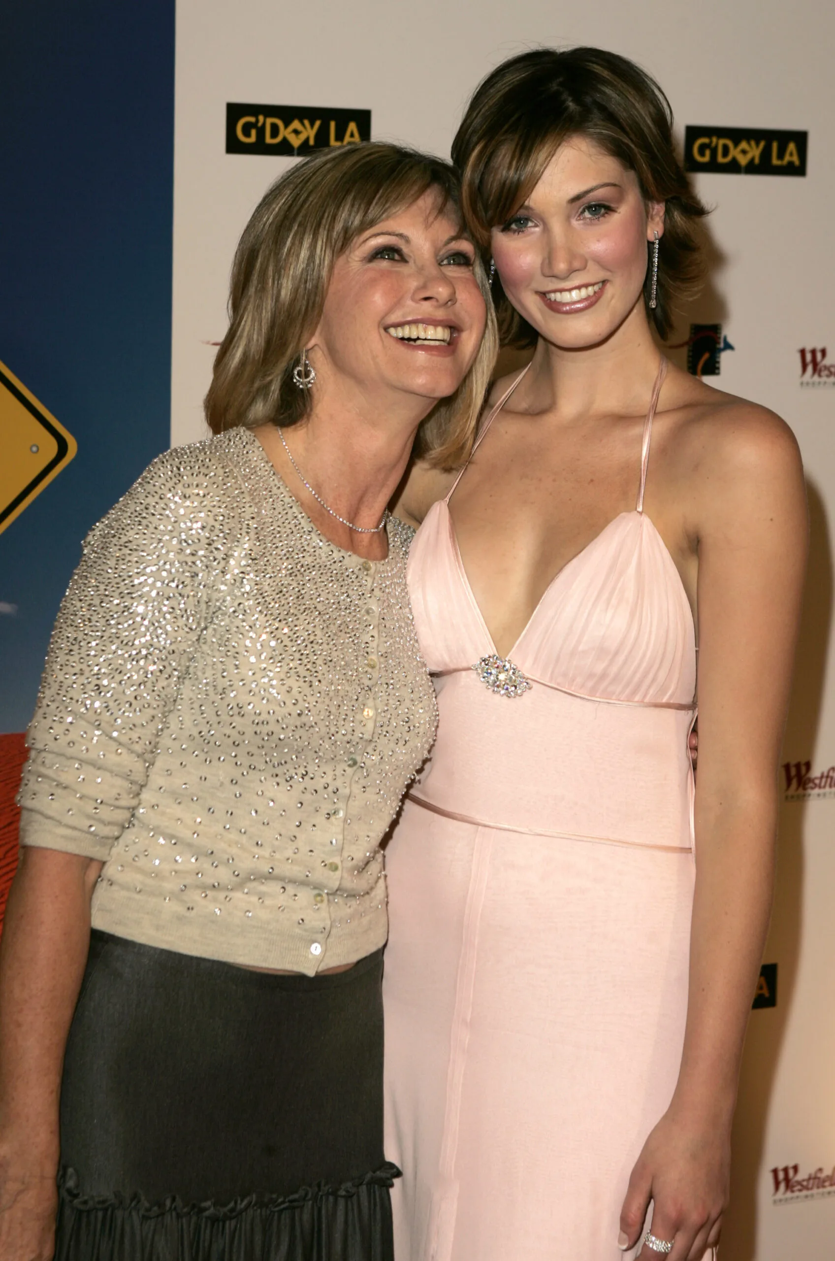 Two women smiling at an event, posing for a photo, elegantly dressed.