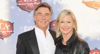 Couple smiling at the American Country Awards, man in black suit and woman in black leather jacket.