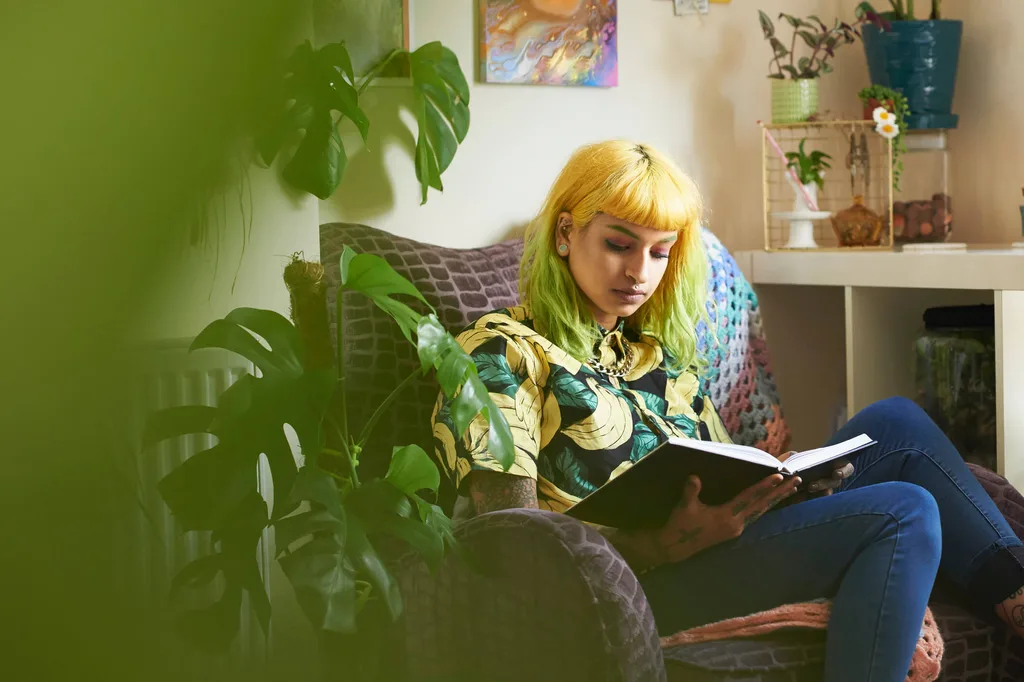 Girl with orange and green hair sitting in sofa reading