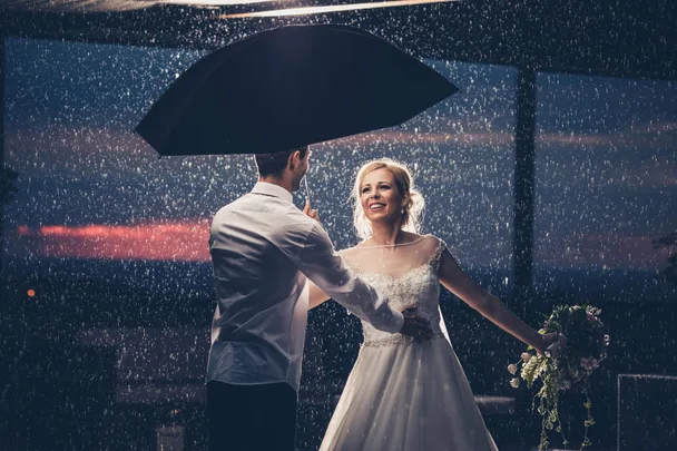 A newlywed couple under an umbrella
