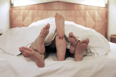3 people under a doona cover in bed