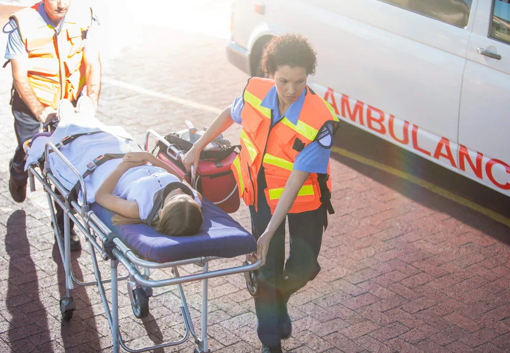 A paramedic wheeling a patient to an ambulance