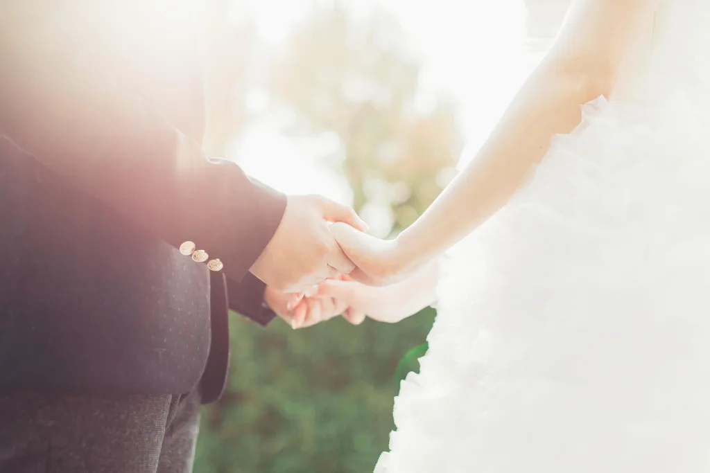 A bridge and groom holding hands on a sunny day