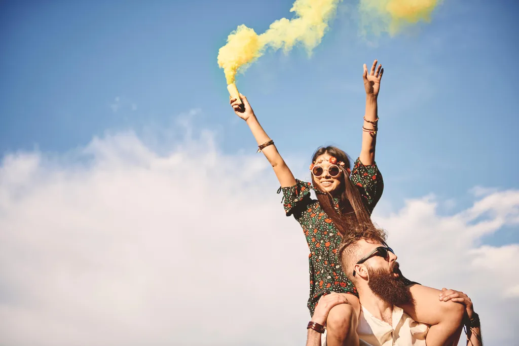 A girl wearing boho style with a smoke flare on a man's shoulders