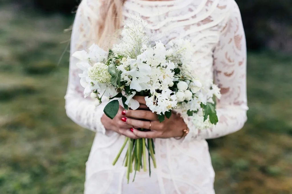 Woman in a boho flower dress holding bunch of white flowers