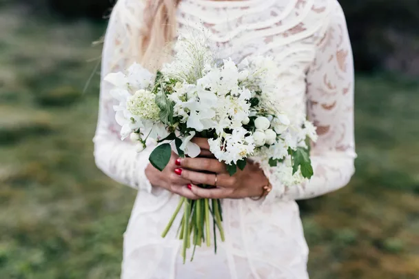Woman in a boho flower dress holding bunch of white flowers