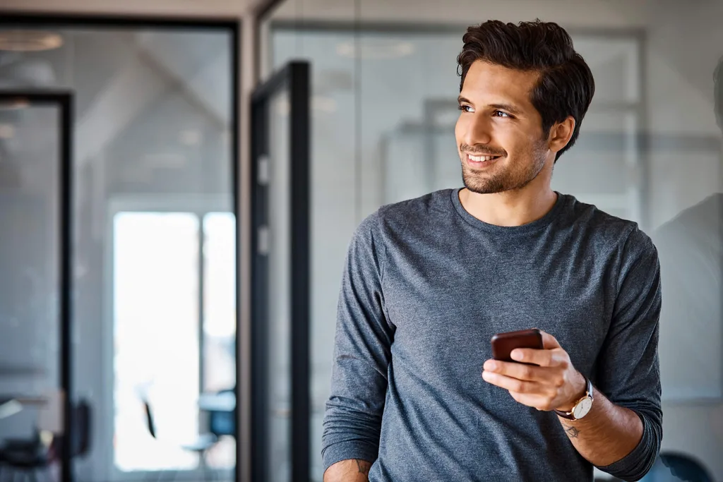 Smiling millennial guy holding phone