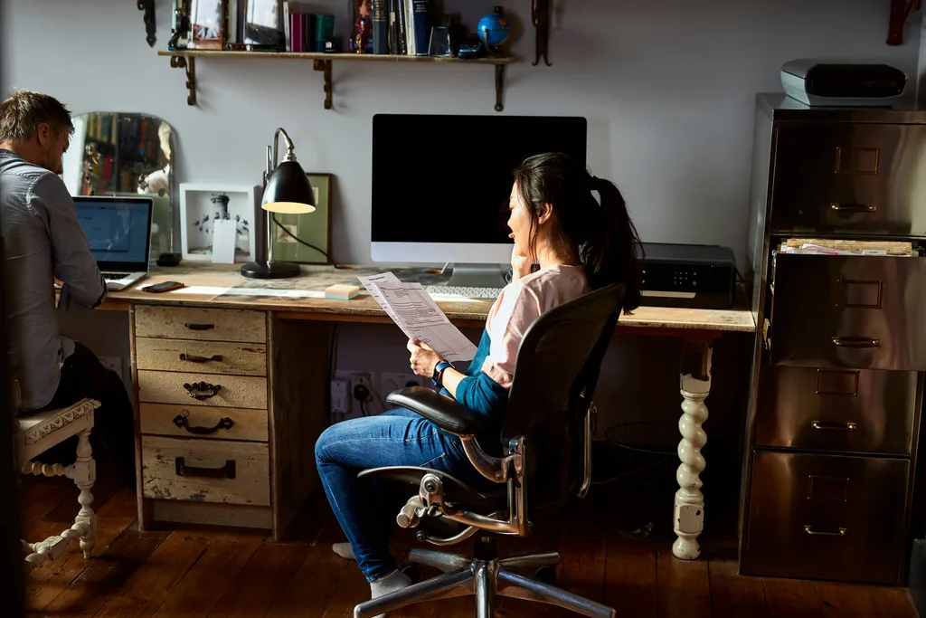 Young girl in overalls reading papers at a desk