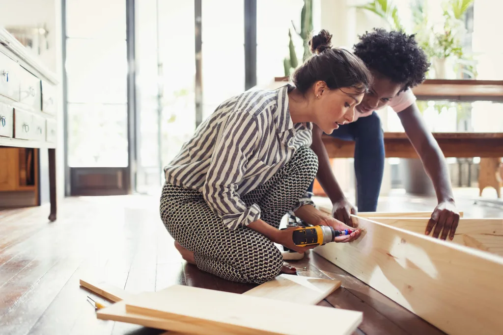 A woman using a drill to screw two pieces of wood together