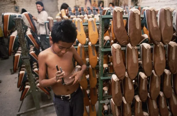 Young boy making shoes in a sweatshop