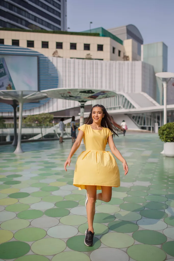 Girl in yellow dress running across green tiles