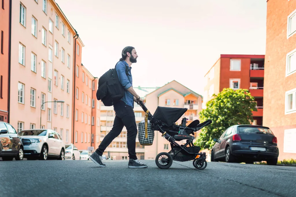 Father walking across street with baby in a pram