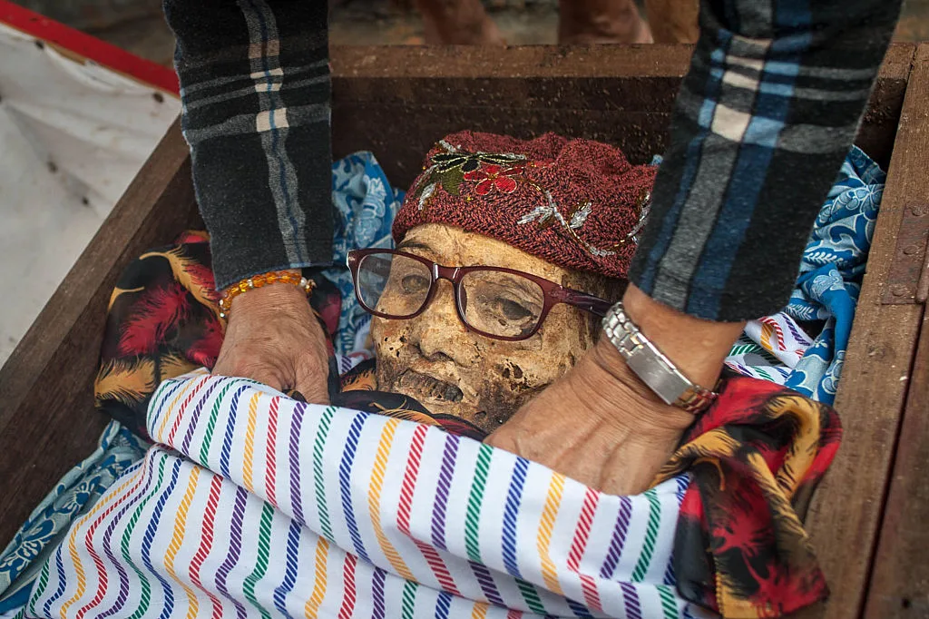 A woman changing the clothing and cleaning the body of a mummy