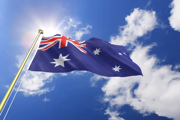 An Australian flag flying against a blue cloudy sky