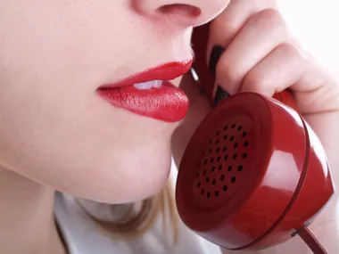 Woman with red lipstick holding a red phone up to her face