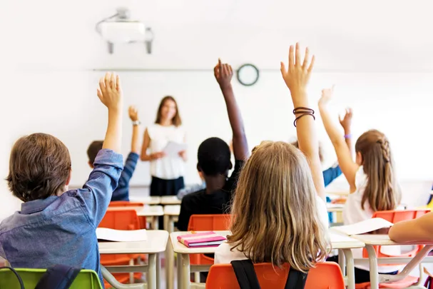 A classroom of children with their hand's raised