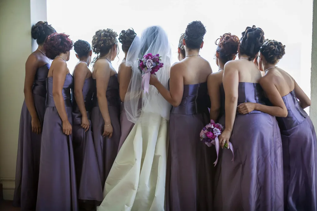 A group of bridesmaids in purple dresses with a bride