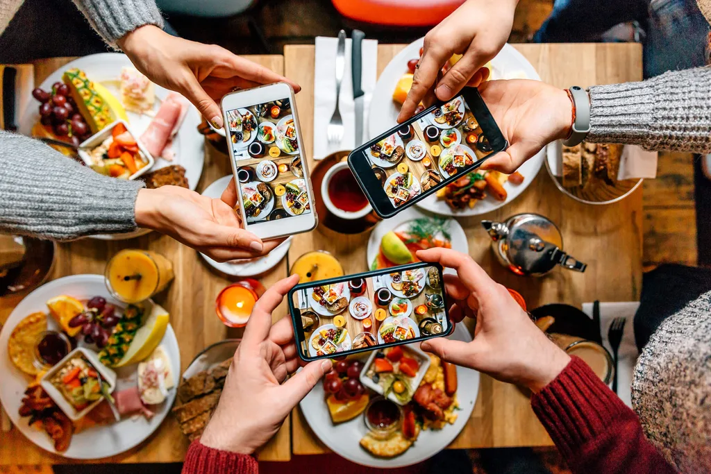 A group of friends taking photos of their meals for Instagram