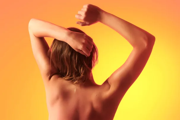 Woman stretching in front of an orange background