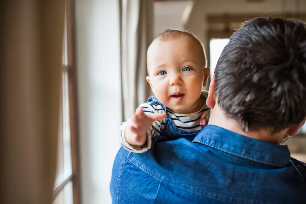A baby looking over the shoulder of their dad