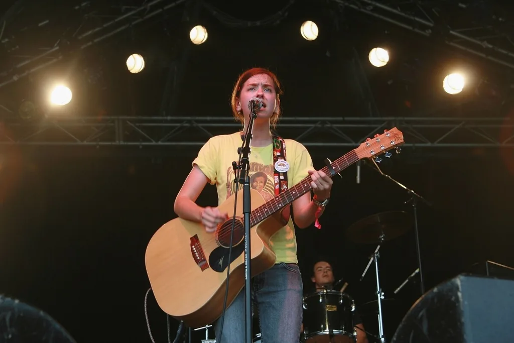 Laura Imbruglia singing on stage with an acoustic guitar