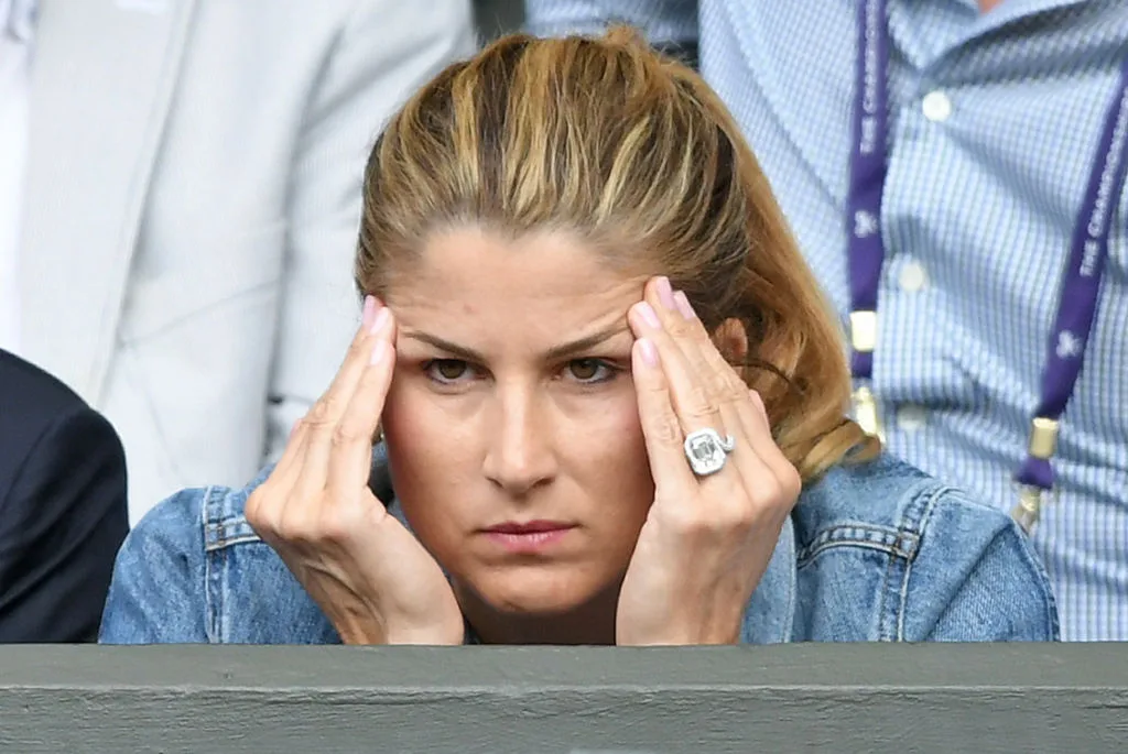 Mirka Federer rubbing her temples at a tennis game