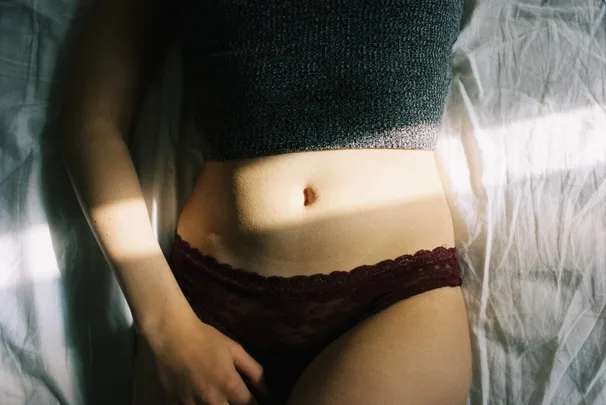A woman wearing underwear and a woolen top in bed