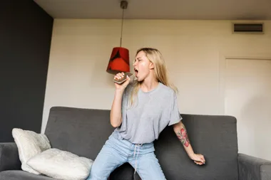 A young woman singing on her couch