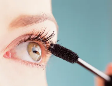 Woman applying mascara to her eyelashes