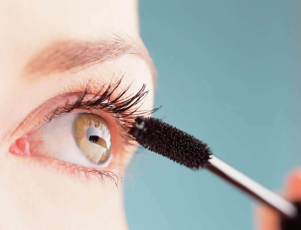 Woman applying mascara to her eyelashes