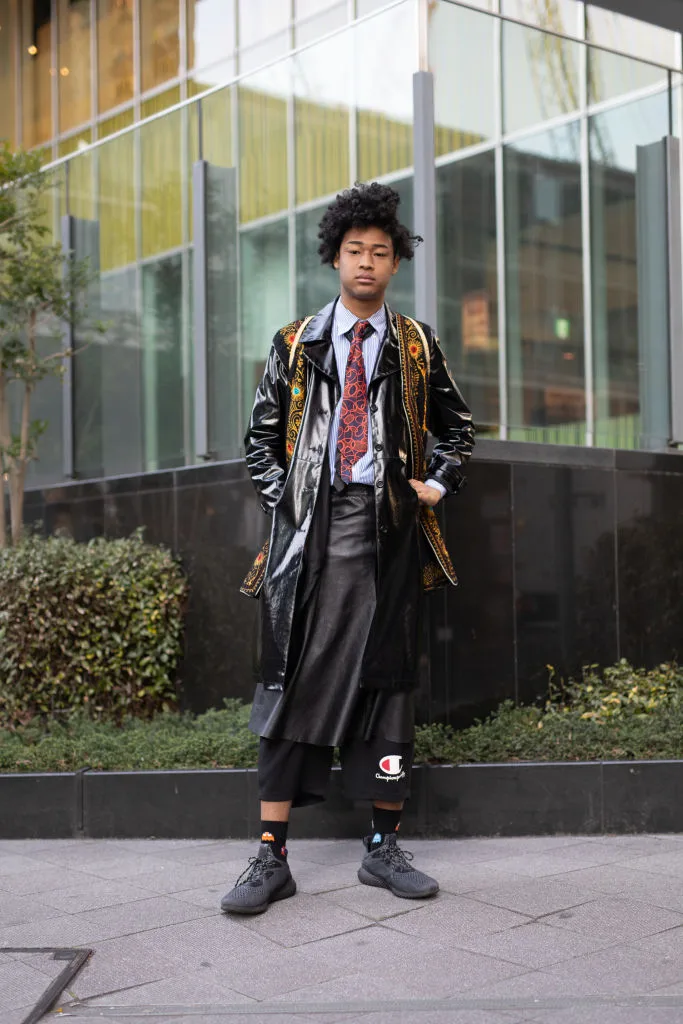 A guest at the Amazon Fashion Week TOKYO wearing a black and gold coat