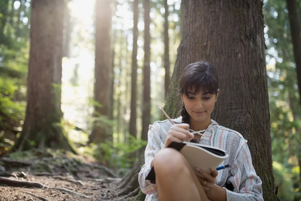 A woman writing in a journal in a forest