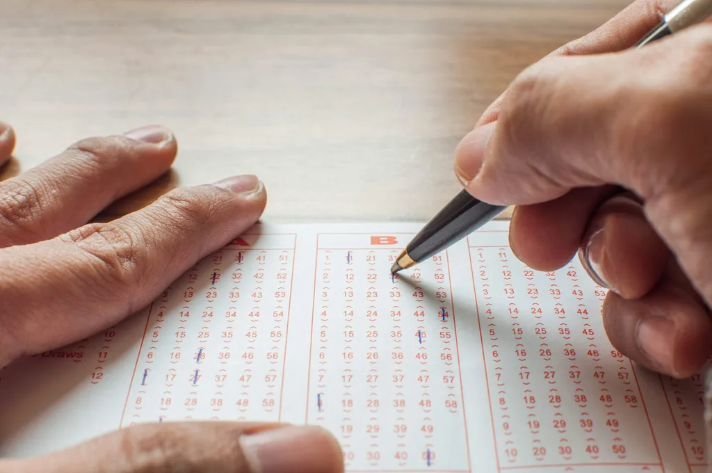 A person crossing off numbers on a lottery ticket