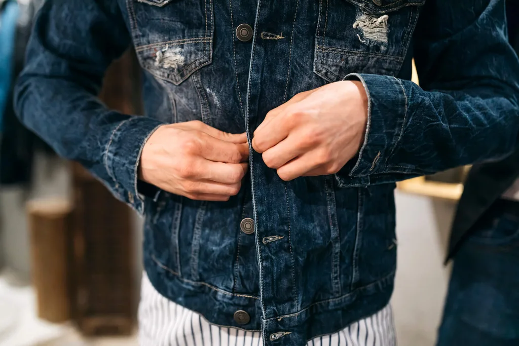 A man putting on a denim jacket