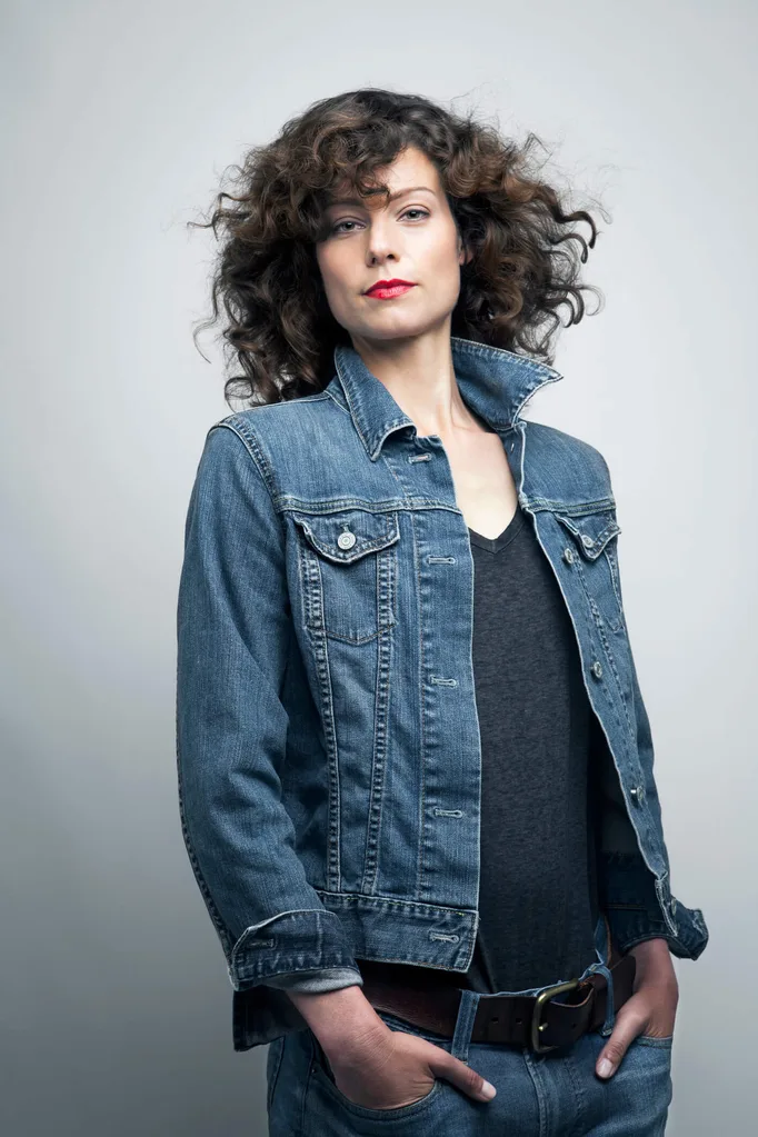 A woman wearing a denim jacket, dark coloured shirt and denim jeans