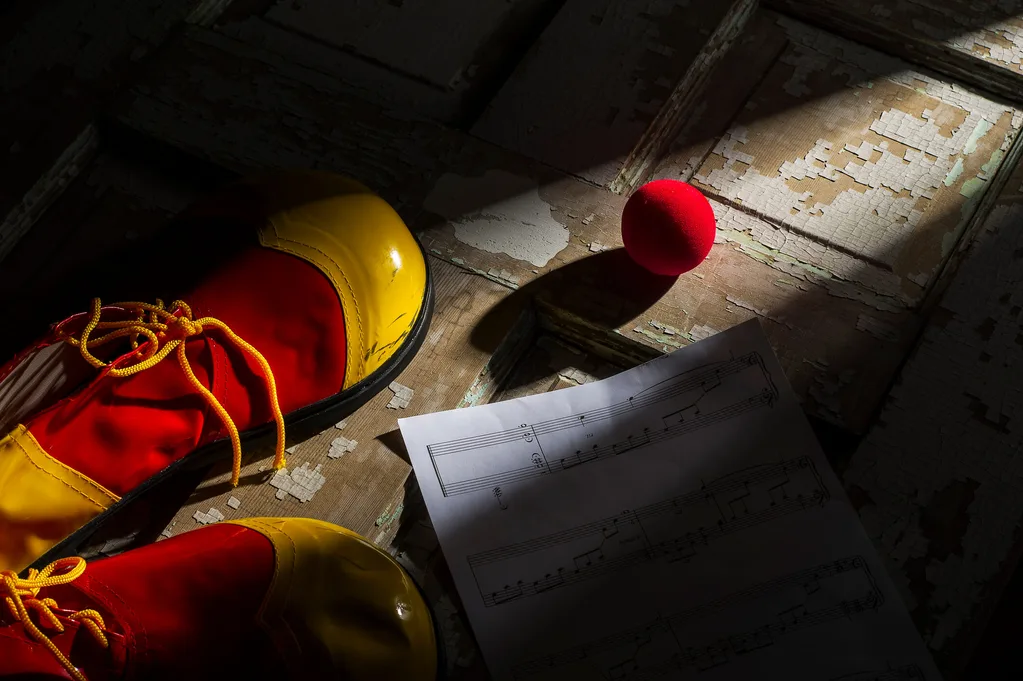 Red and yellow clown shoes on wooden floorboards
