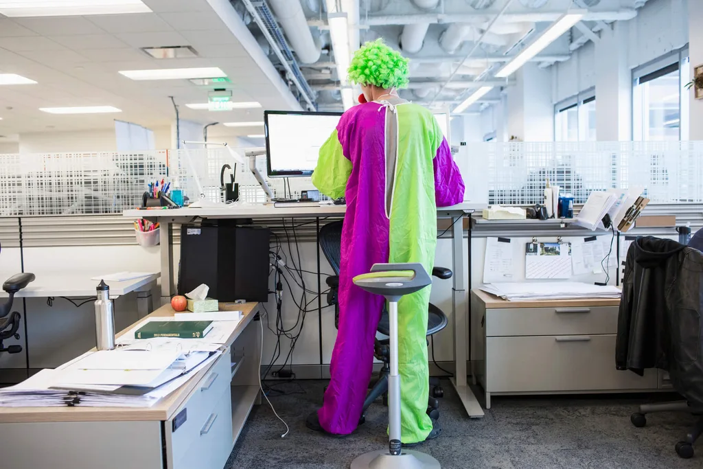 A clown dressed in a purple and green suit in an office