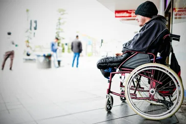 A young man in winter clothing in a wheelchair on the street