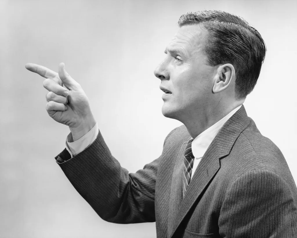 A man in a tweed suit pointing his finger
