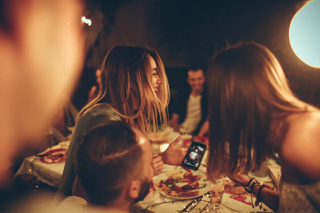 Girls laughing while looking at their phone over dinner