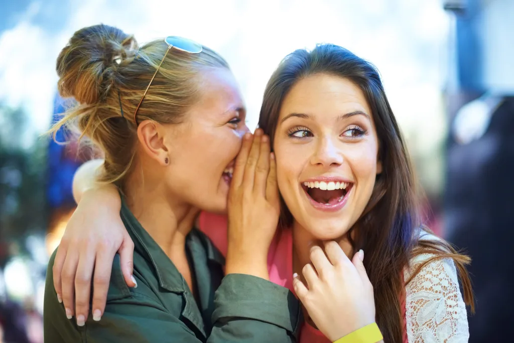 A girl whispering into her friend's ear