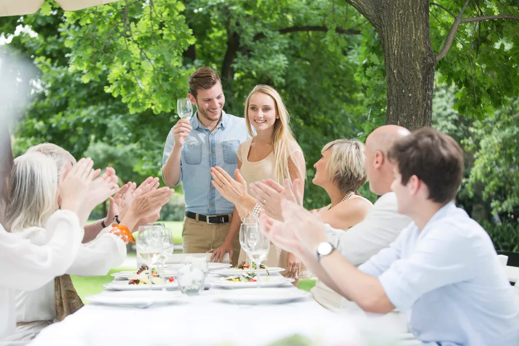 Friends around a table clapping for a young couple