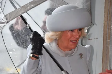 Grimacing Camilla caught out in pouring rain