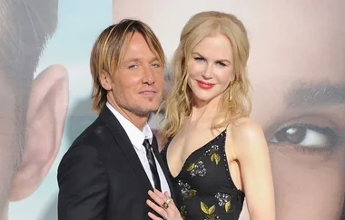 Keith Urban and Nicole Kidman pose together on the red carpet, Keith in a suit and Nicole in a black floral dress.