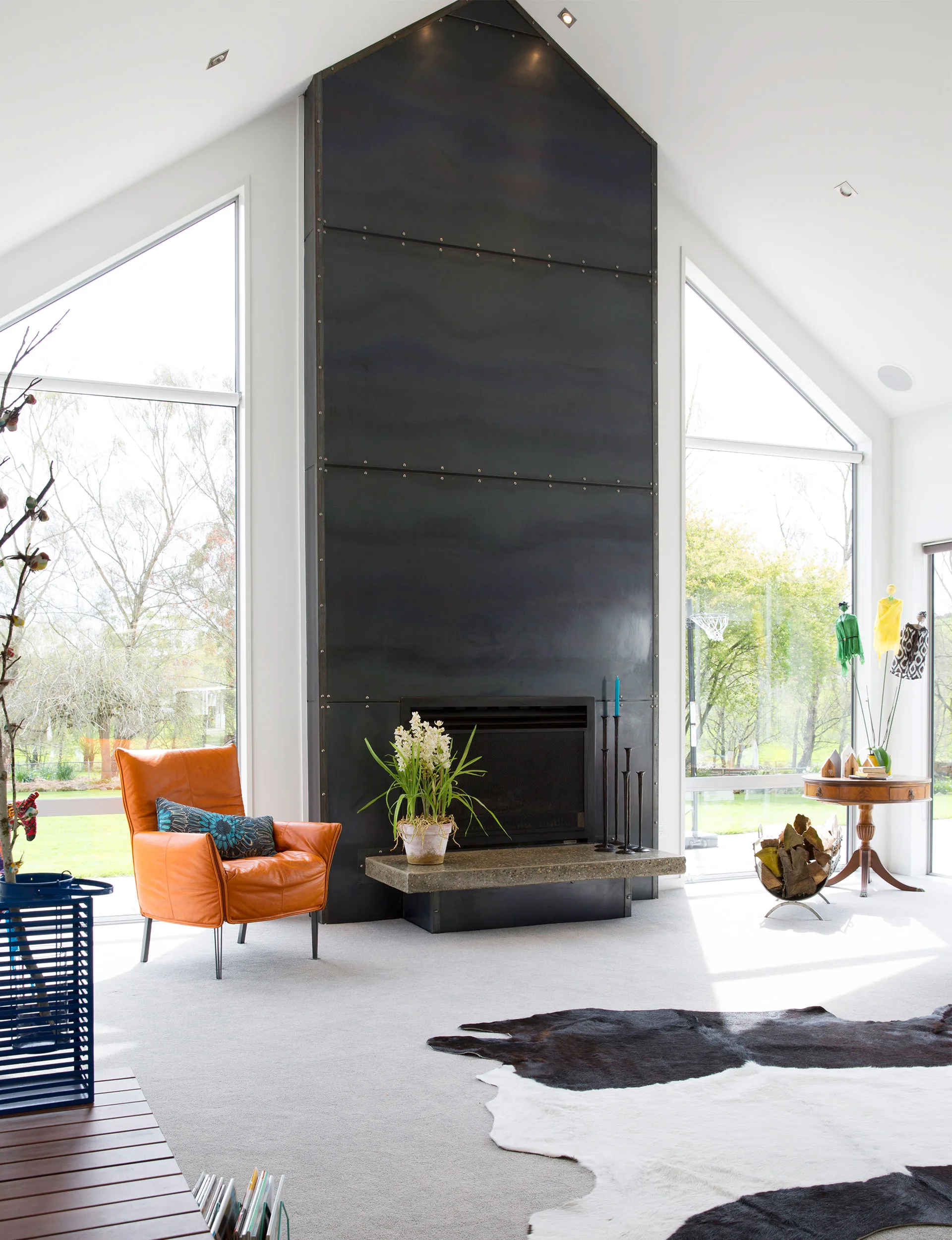 The airy living room is dominated by a massive steel fireplace on the northern wall with windows on either side overlooking the lawns. 