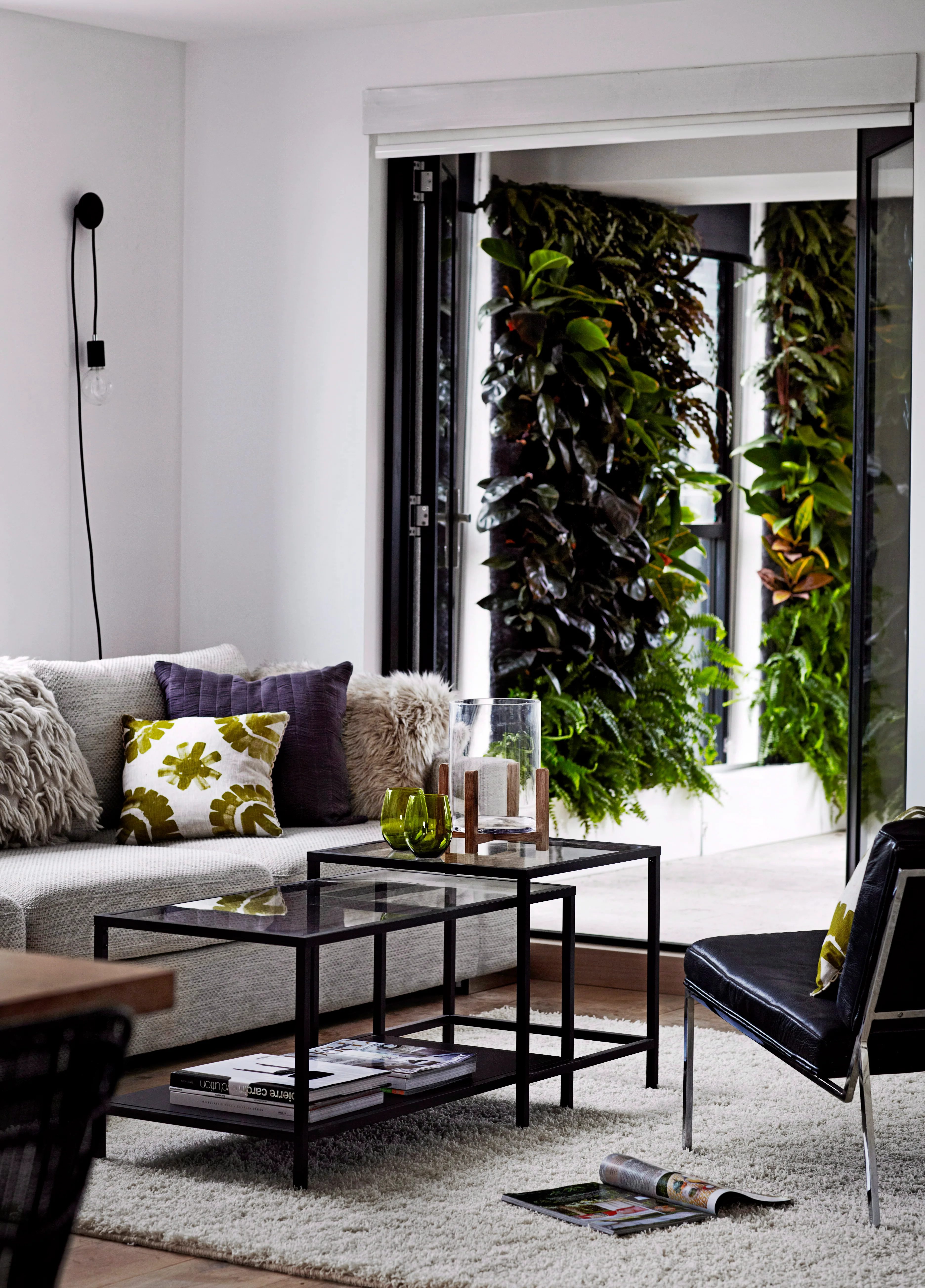 The living room is a laidback space with versatile furniture and a verdant outlook thanks to the green walls.
