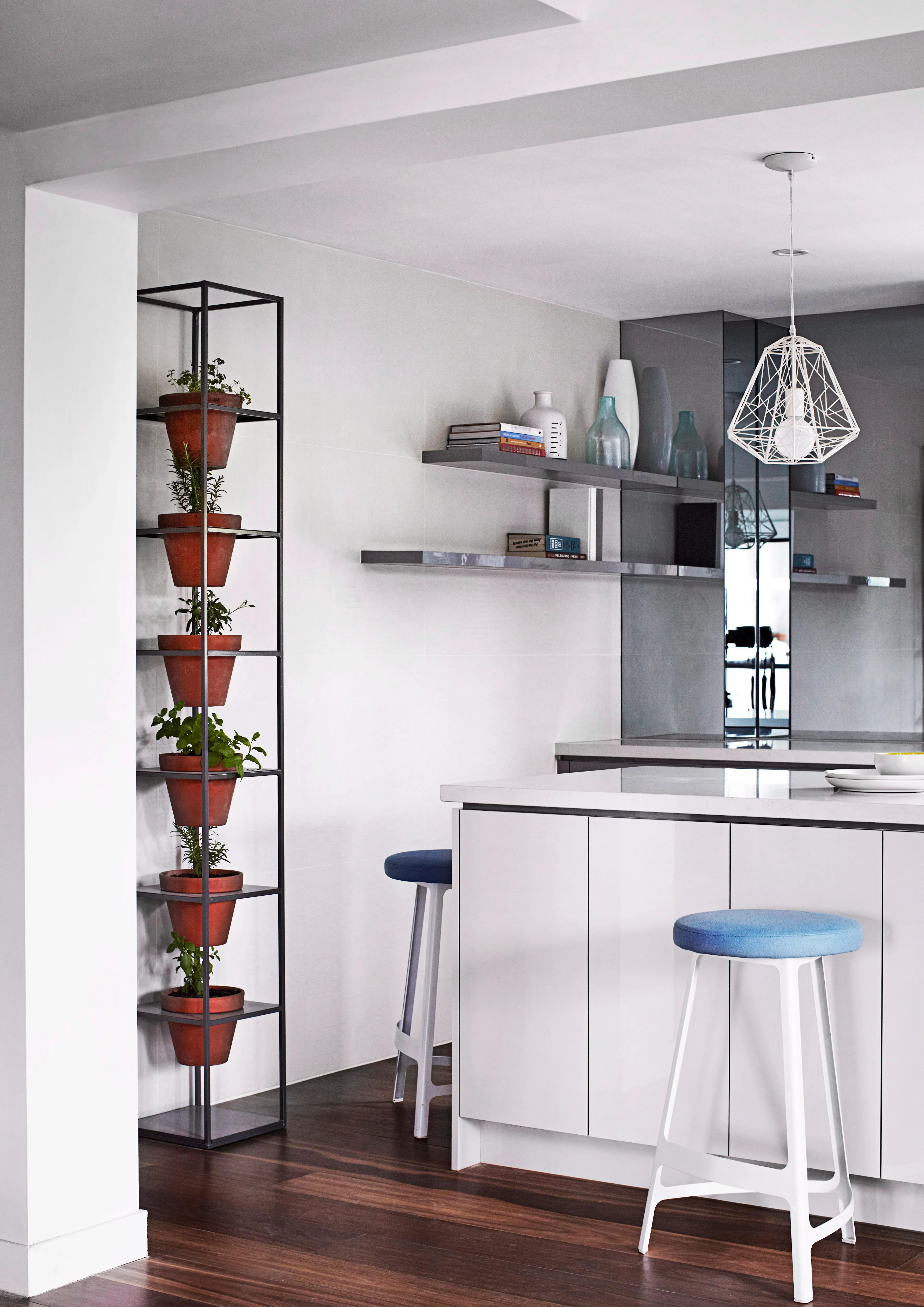 Slick surfaces combine in the kitchen, with grey open shelves and a Caesarstone ‘Frosty Carrina’ benchtop. The ‘Factory’ stools are by Sean Dix.